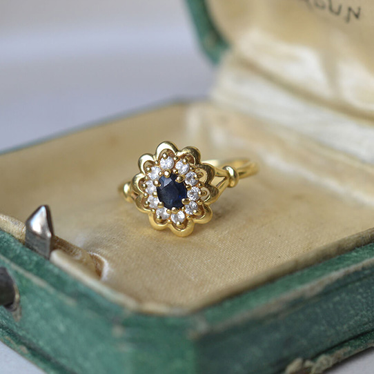 Bague marguerite en Or jaune centrée d'un saphir monté en serti griffé et entouré d'oxydes Noir Carat
