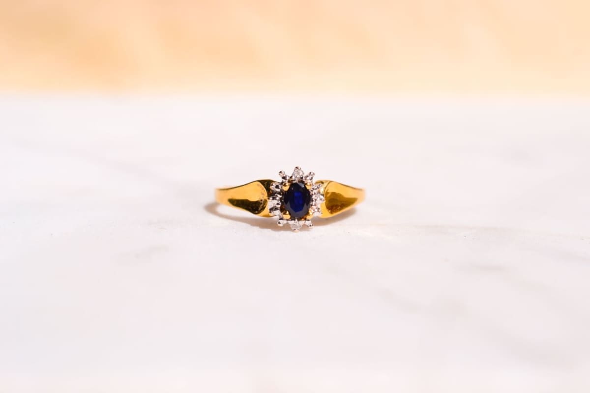 Bague Marguerite en Or jaune 18 carats centrée d'un Saphir serti griffes entouré de 2 Diamants dans la hauteur et d'un pavage dans la largeur