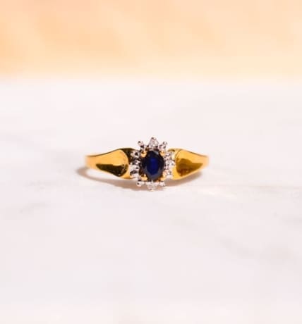 Bague Marguerite en Or jaune 18 carats centrée d'un Saphir serti griffes entouré de 2 Diamants dans la hauteur et d'un pavage dans la largeur