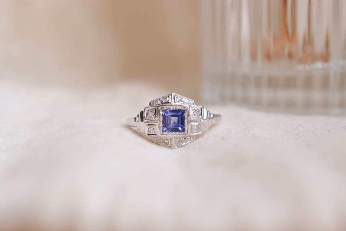Bague style Art Déco en Or blanc 18 carats et Platine de forme hexagonale sertie d'un Saphir bleu jean carré dans un entourage de Diamants