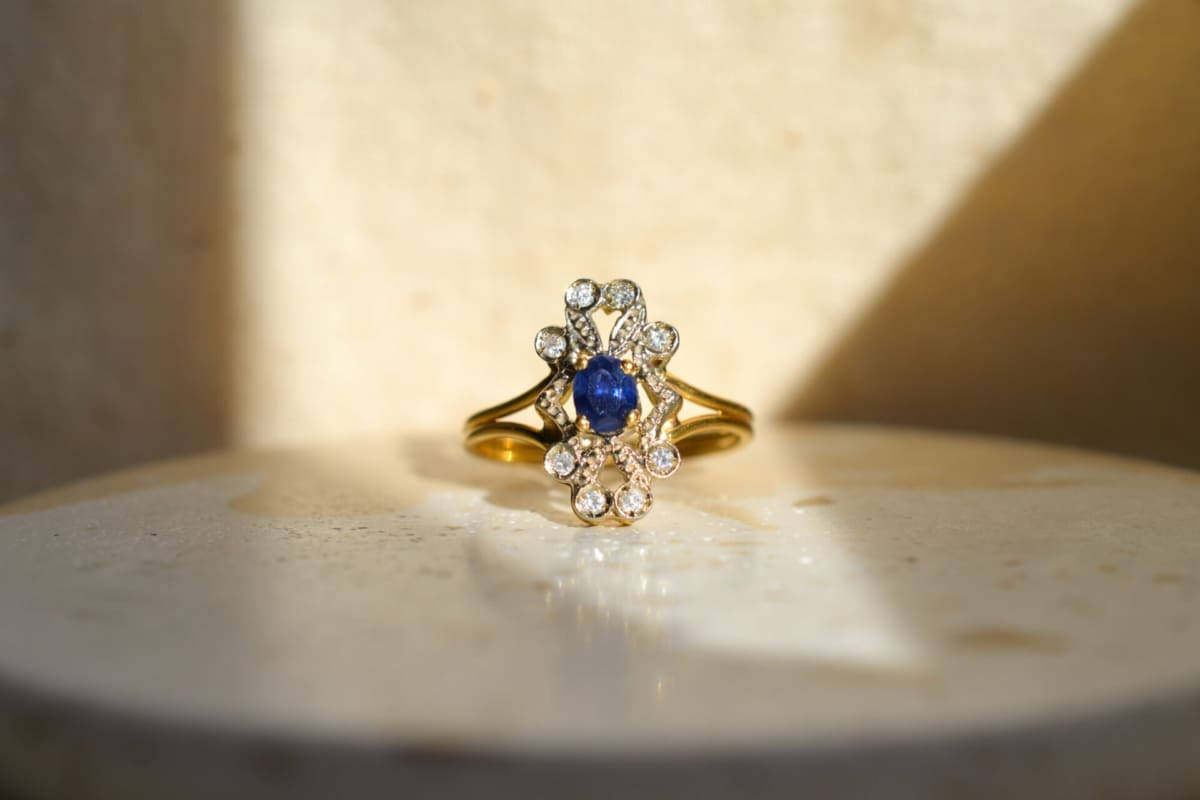 Bague Marguerite ajourée en Or jaune 18 carats centrée d'un Saphir serti griffes dans un entourage de Diamants