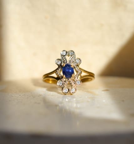 Bague Marguerite ajourée en Or jaune 18 carats centrée d'un Saphir serti griffes dans un entourage de Diamants