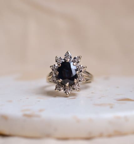 Bague Marguerite en Or blanc 18 carats sertie griffes d'un Saphir taille ovale dans un entourage de Diamants