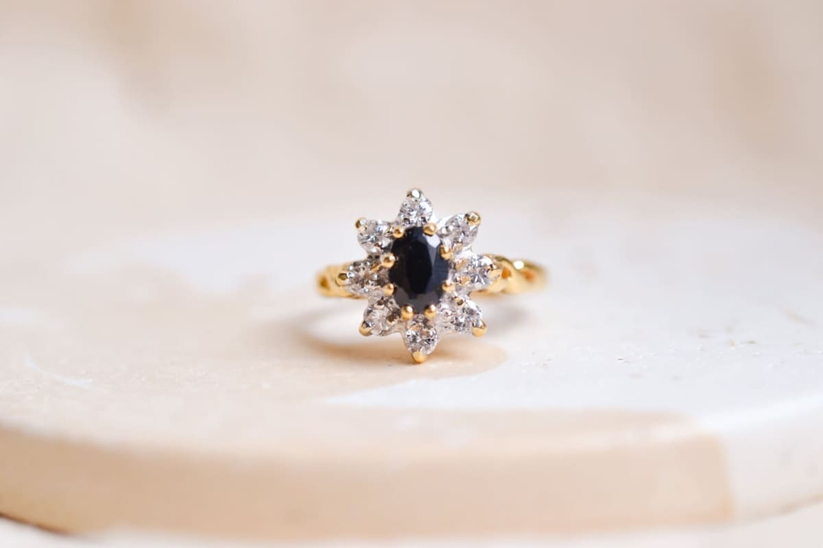 Bague Marguerite en Or jaune centrée d'un Saphir entouré de Diamants, avec une monture torsadée formant les signes de l'infini