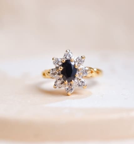 Bague Marguerite en Or jaune centrée d'un Saphir entouré de Diamants, avec une monture torsadée formant les signes de l'infini