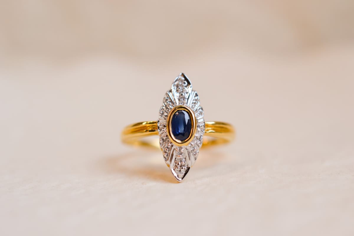 Bague Marquise en Or jaune 18 carats centrée d'un Saphir serti clos en Or jaune sur une illusion de pavage en Or blanc