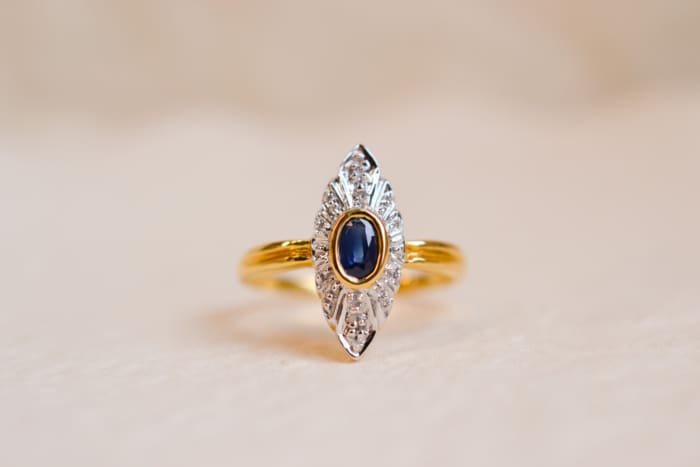 Bague Marquise en Or jaune 18 carats centrée d'un Saphir serti clos en Or jaune sur une illusion de pavage en Or blanc