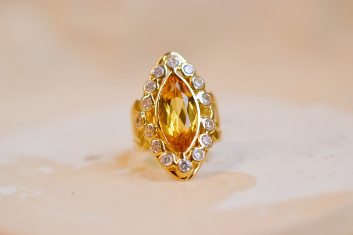 Bague Marquise en Or jaune centree d'un Saphir jaune entouré de pierres blanches