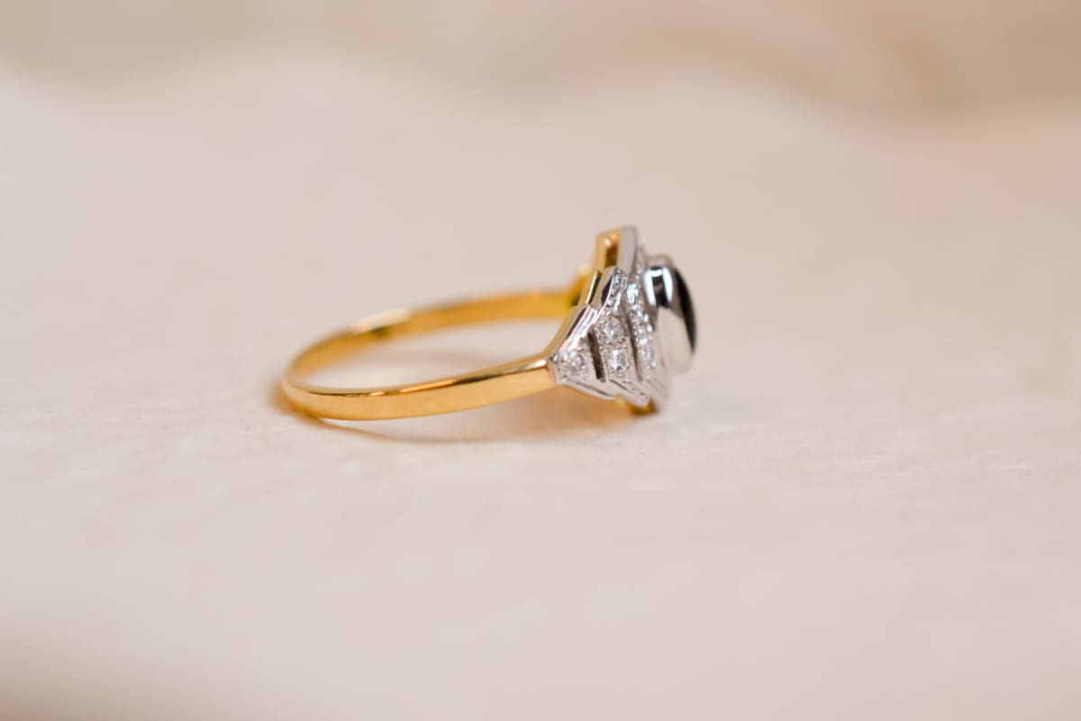 Bague ancienne en Or jaune et blanc 18 carats sertie clos d'un cabochon d'Onyx entouré de Diamants