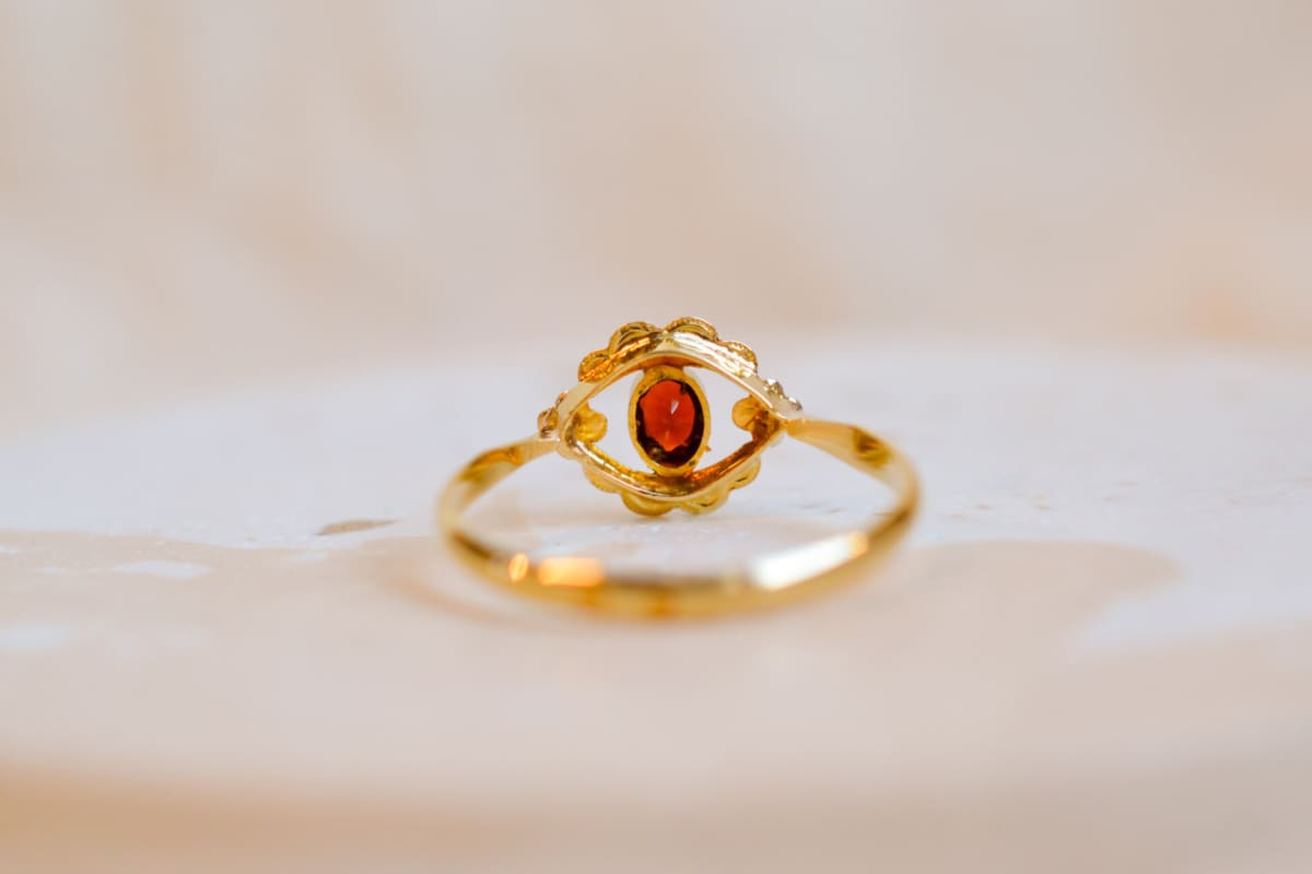 Bague en Or jaune 18 carats ornée d'un Grenat serti clos sur une table ajourée en fleurettes en Or blanc