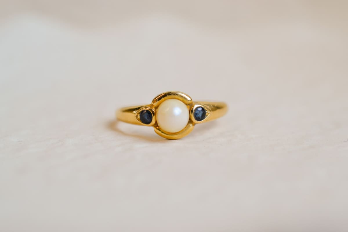 Bague jonc en Or jaune 18 carats centrée d'une Perle épaulée de pierres bleues