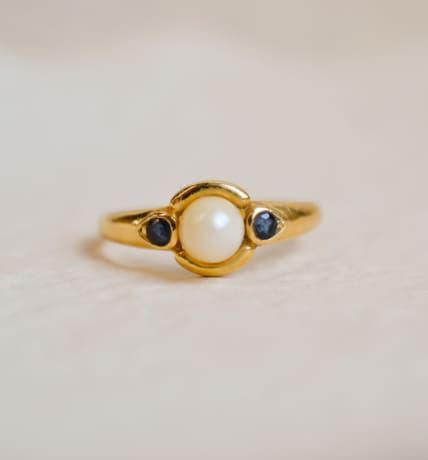 Bague jonc en Or jaune 18 carats centrée d'une Perle épaulée de pierres bleues