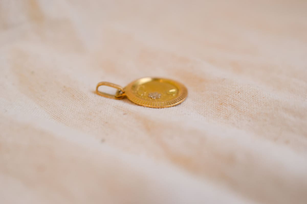 Médaille ancienne en Or jaune 18 carats à décor floral dans un entourage rainuré