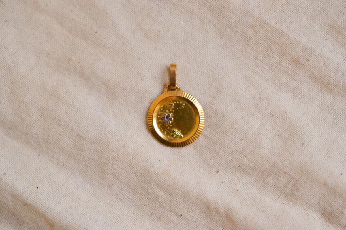 Médaille en Or jaune 18 carats à décor floral et entourage rainuré