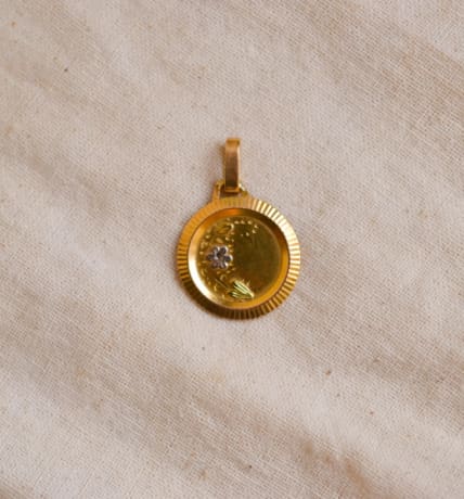 Médaille en Or jaune 18 carats à décor floral et entourage rainuré