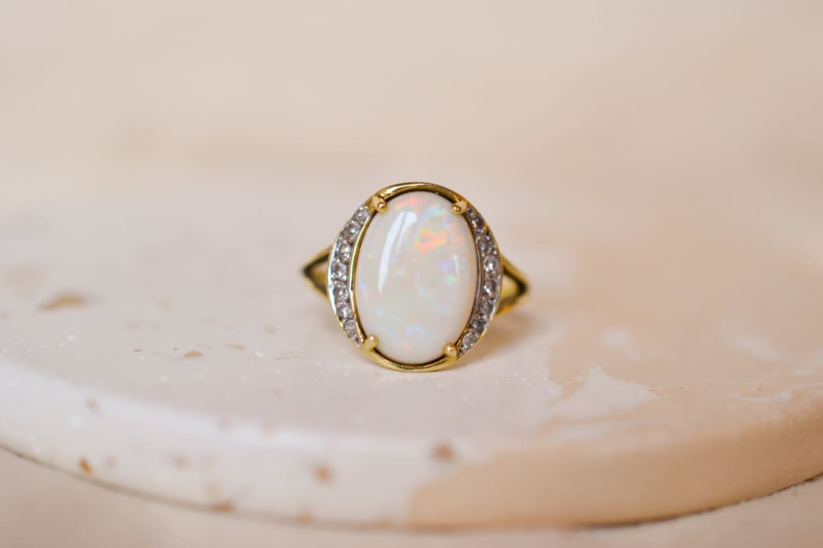 Bague ancienne en Or jaune 18 carats sertie griffes d'une Opale épaulée par des lignes de Diamants