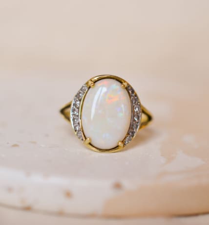 Bague ancienne en Or jaune 18 carats sertie griffes d'une Opale épaulée par des lignes de Diamants