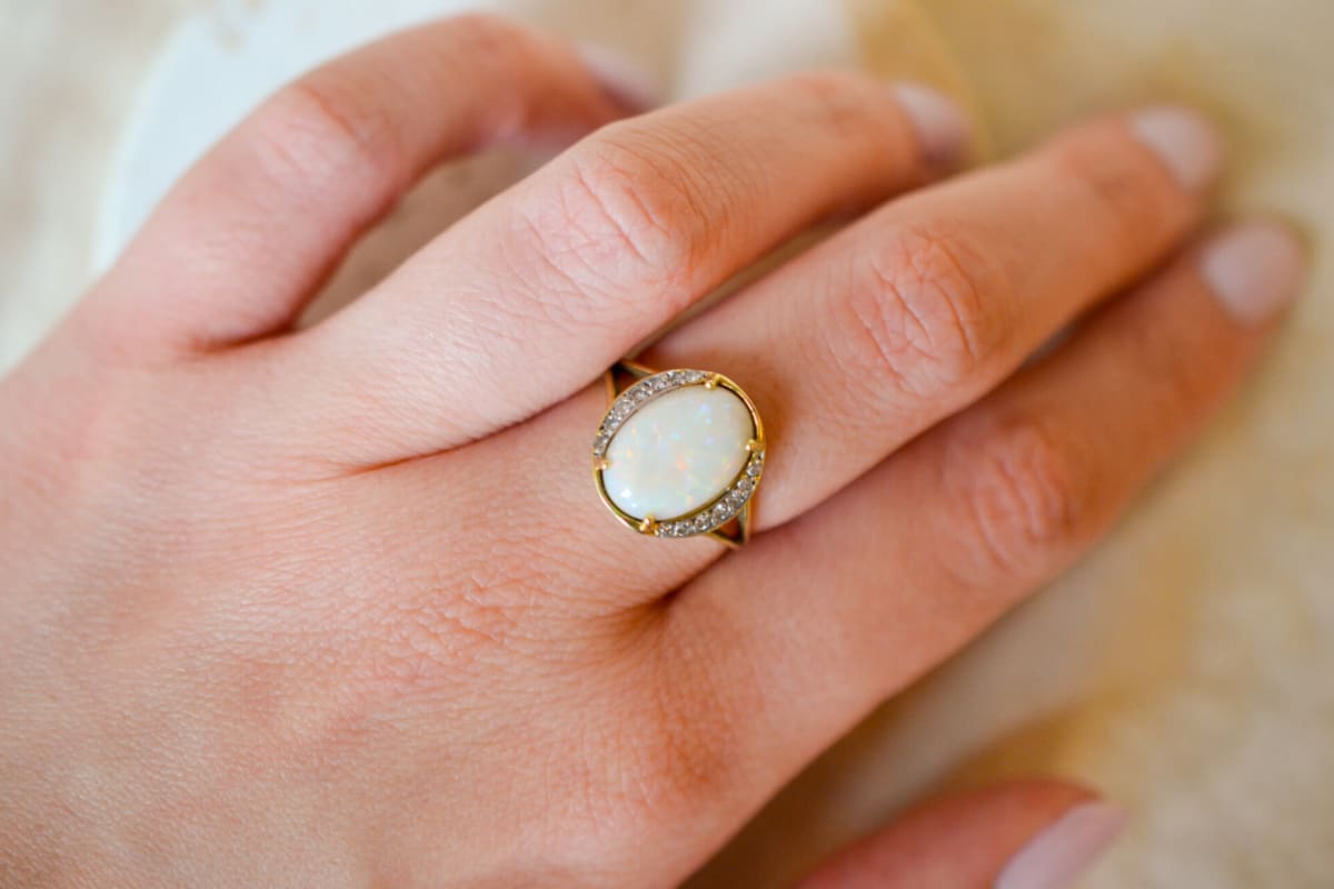 Bague de fiançailles ancienne en Or jaune 18 carats sertie griffes d'une Opale épaulée par des lignes de Diamants