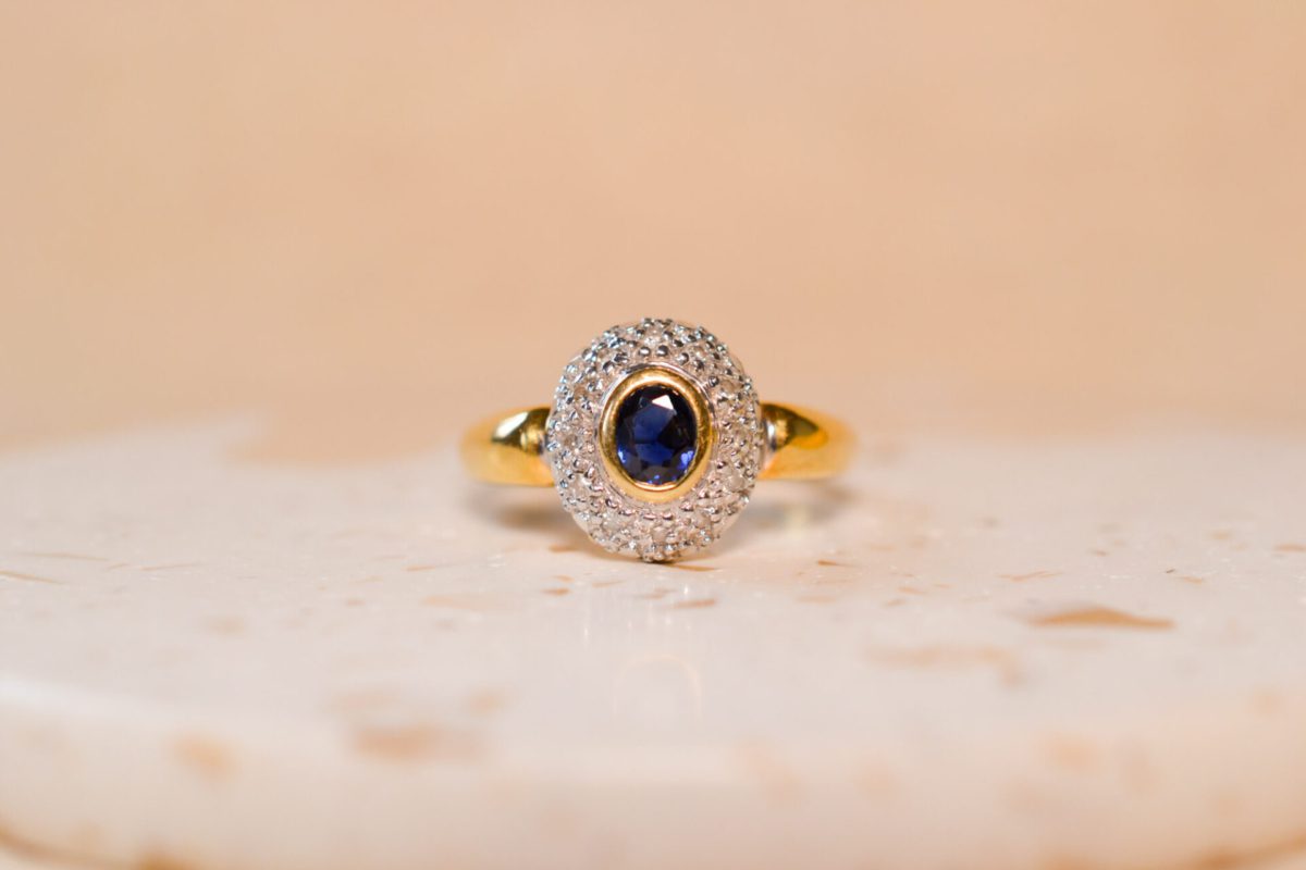 Bague ancienne en Or jaune 18 carats centrée d'un Saphir dans un pavage de Diamants en Or blanc
