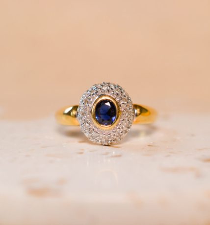Bague ancienne en Or jaune 18 carats centrée d'un Saphir dans un pavage de Diamants en Or blanc